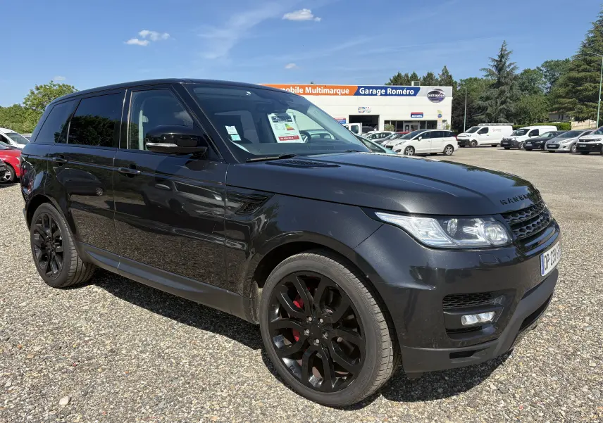 Vue 3/4 avant gauche d’un Range Rover Sport 2015 noir avec jantes noires et cales de frein rouges, stationné sur un parking.