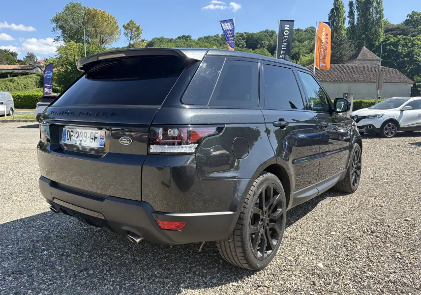 Vue 3/4 arrière droite d'un Range Rover Sport 2015 gris foncé avec jantes noires et vitres teintées.