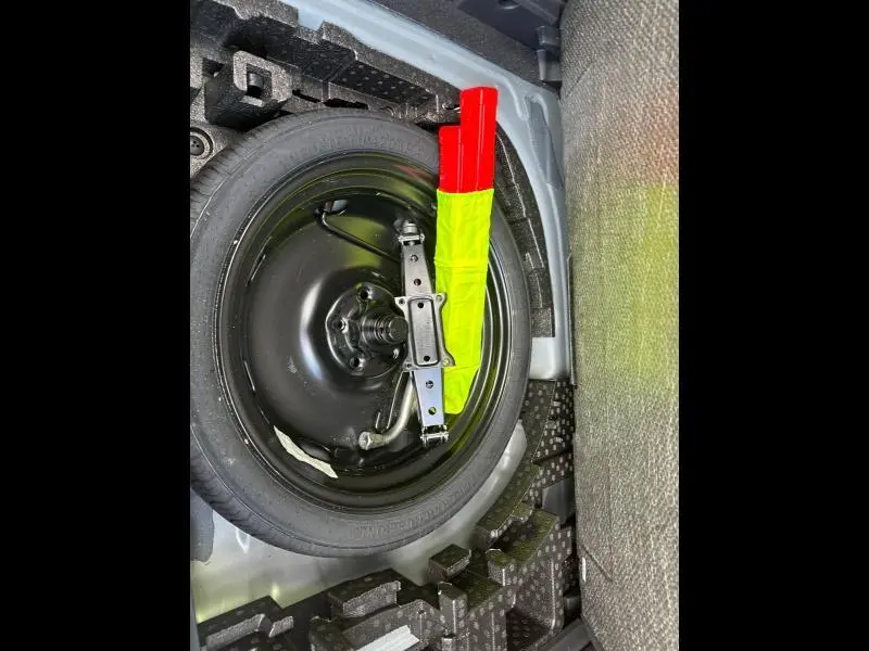 Vue rapprochée de la roue de secours noire et du cric avec gilet de sécurité jaune et rouge dans le coffre d'une CUPRA Formentor.