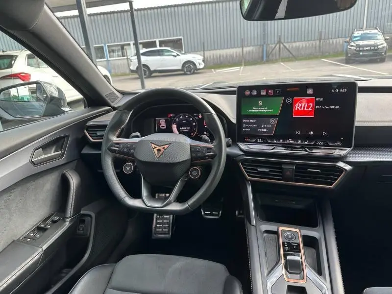Vue intérieure avant du CUPRA Formentor 1.5 eTSI Hybrid 2025, volant cuir sport et écran tactile central allumé.