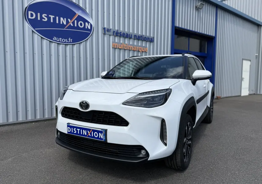 Toyota Yaris Cross blanc vue 3/4 avant droit, avec calandre noire et jantes bi-ton noires visibles.