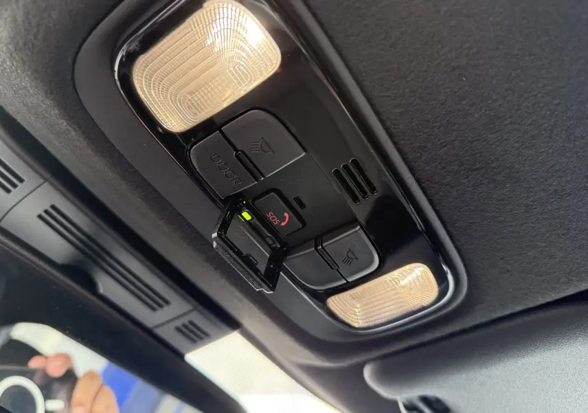 Détail du plafonnier intérieur noir avec éclairages et bouton SOS activé dans une Toyota Yaris Cross blanche 2024.