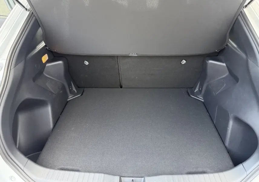 Coffre ouvert vu de l'arrière d'une Toyota Yaris Cross 130 CH Design blanche, espace de chargement vide et propre.