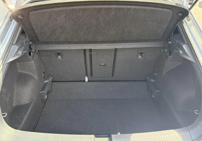 Coffre ouvert vu de l'arrière d'un Volkswagen T-Roc gris Pyrite, montrant un espace de rangement propre et spacieux.