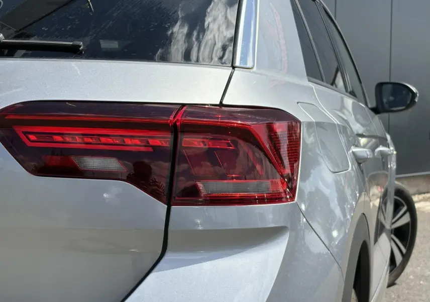 Vue 3/4 arrière droite du Volkswagen T-Roc gris pyrite avec feux arrière LED et jantes alliage visibles.