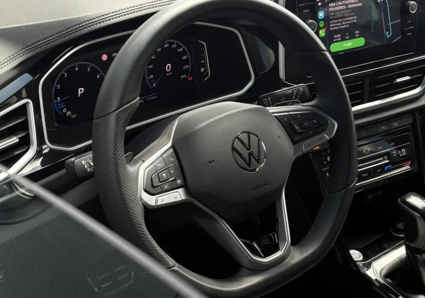 Vue rapprochée du volant cuir noir multifonction Volkswagen T-Roc 2025 avec tableau de bord digital et écran tactile Apple Car Play.