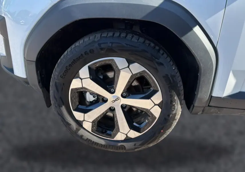 Gros plan sur la roue avant droite du Dacia Bigster blanc, avec jante alu bicolore et pneu Continental.