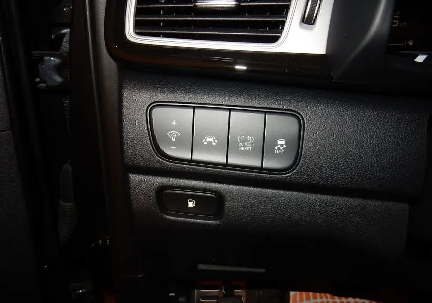 Gros plan sur les commandes côté gauche du tableau de bord noir du Kia Niro hybride 2019, avec boutons de réglage et ouverture carburant.