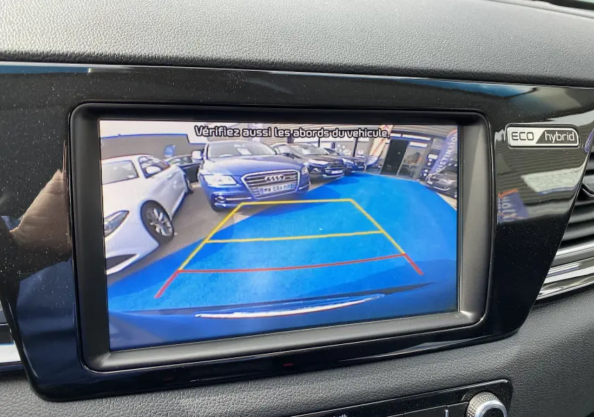 Vue de la caméra de recul du KIA Niro gris galène, affichant le parking avec des lignes de guidage colorées.