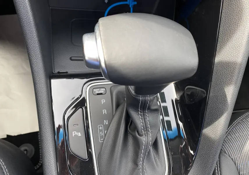 Le levier de vitesses automatique noir du KIA Niro hybride 2019, vu de dessus avec console brillante et coutures visibles.