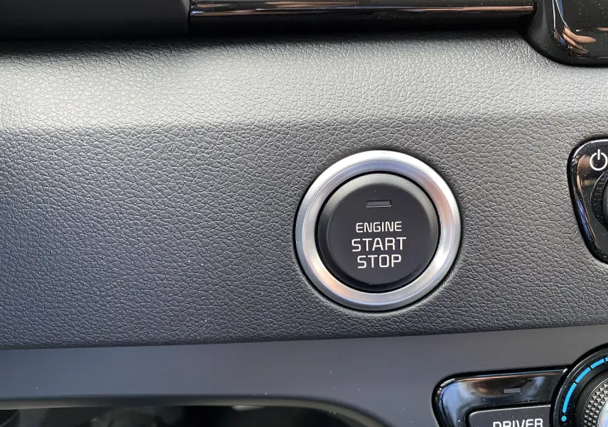Gros plan sur le bouton start/stop du moteur dans l’habitacle du Kia Niro hybride gris galène, tableau de bord texturé noir.