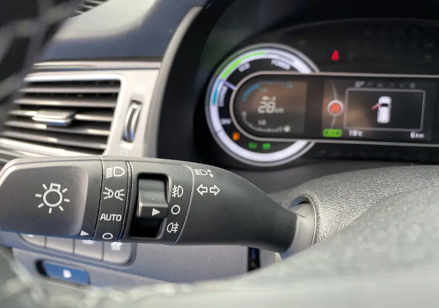 Gros plan sur la commande des feux et clignotants du tableau de bord d’une KIA Niro gris galène hybride 2019.