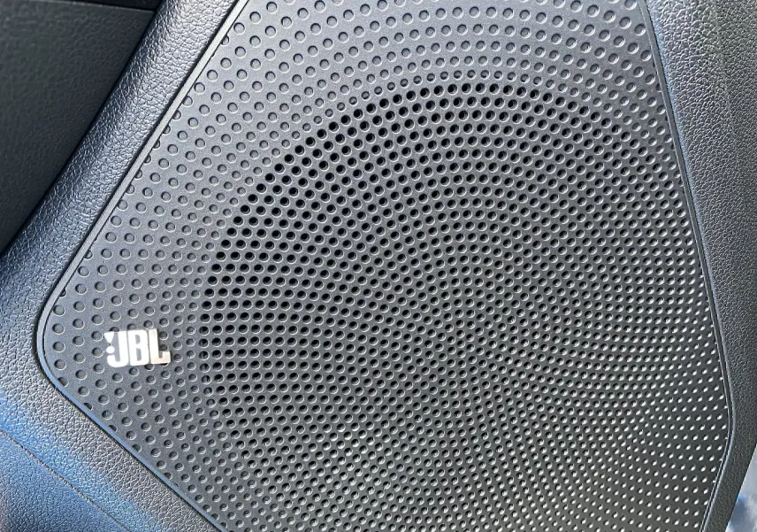 Gros plan sur le haut-parleur JBL intégré dans la porte intérieure noire du Kia Niro hybride gris galène.