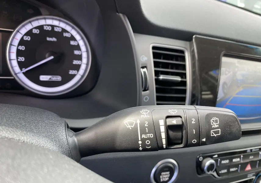 Gros plan sur la commande d’essuie-glace à gauche du volant dans l’habitacle du Kia Niro gris galène 2019.