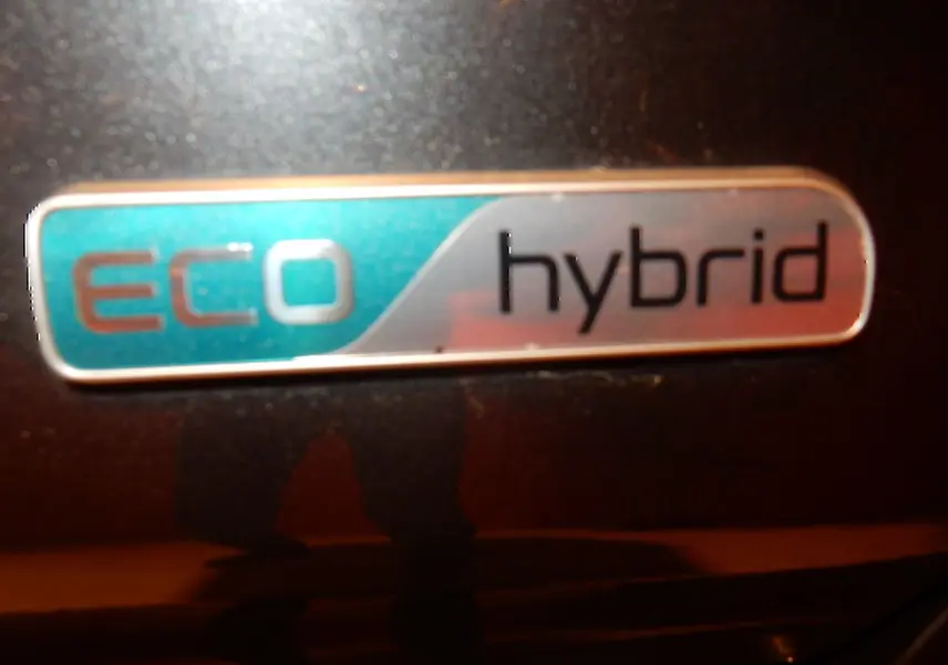 Gros plan sur l’écusson "eco hybrid" sur la carrosserie gris galène métallisé d’une Kia Niro hybride.