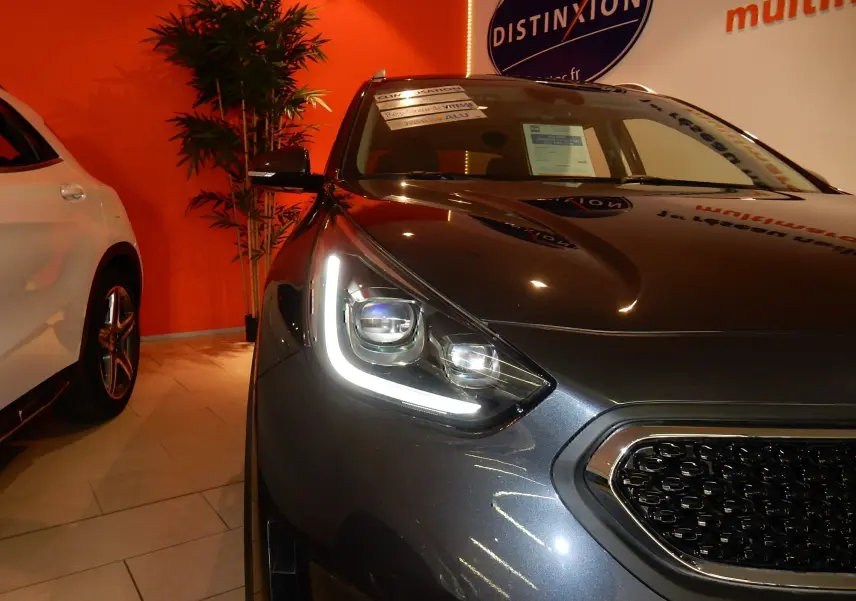 Gros plan sur l'avant droit du Kia Niro hybride gris galène, mettant en valeur le phare LED et la calandre distinctive.