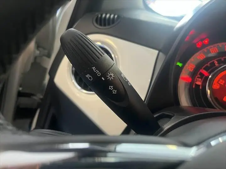 Gros plan sur la commande des phares et clignotants dans l'habitacle noir et blanc de la Fiat 500 2023.
