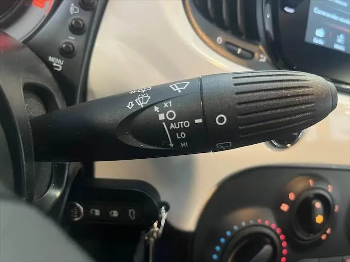 Gros plan sur la commande d'essuie-glace noire dans l'habitacle blanc d'une Fiat 500 hybride 2023.
