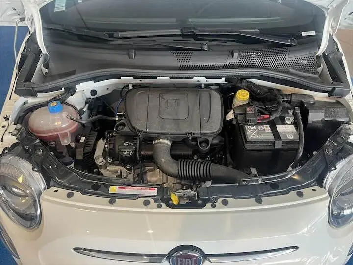 Vue de dessus du moteur du FIAT 500 blanc 2023 avec capot ouvert, montrant le compartiment moteur et batterie.