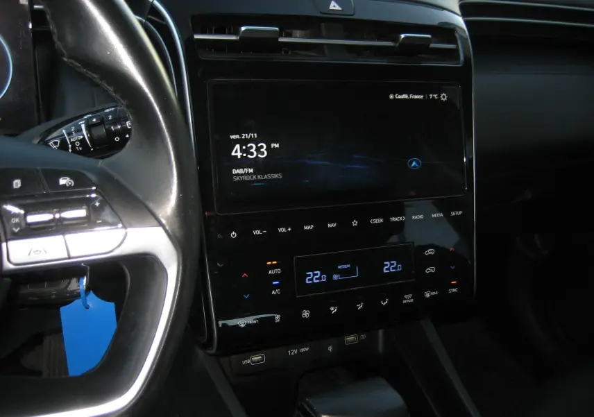 Vue rapprochée de la console centrale et du volant noir du Hyundai Tucson 2022 avec écran tactile et commandes climatisation digitales.