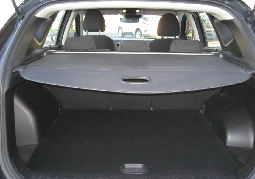 Vue arrière du coffre noir du Hyundai Tucson III 1.6 CRDI hybride 2022 avec cache-bagages déployé.