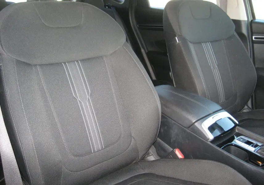 Gros plan sur les sièges avant noirs et la console centrale du Hyundai Tucson III hybride diesel 2022, vue côté droit.