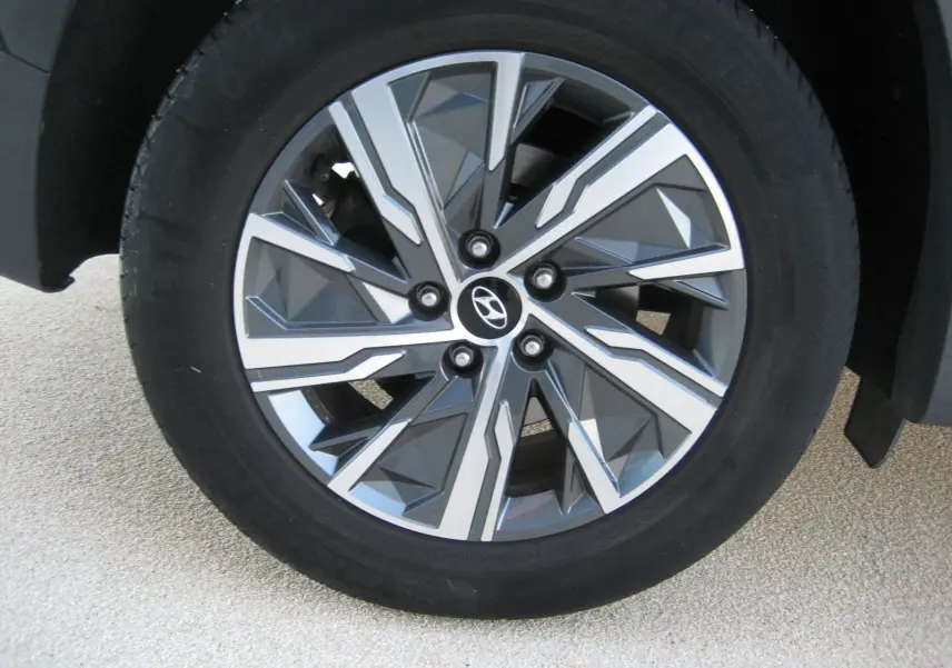 Gros plan sur la jante avant droite du Hyundai Tucson noir 2022, soulignant son design géométrique moderne et le logo Hyundai central.