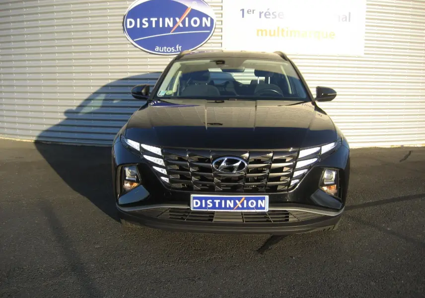 Vue frontale d'un Hyundai Tucson noir 2022 avec calandre large et feux LED distinctifs allumés.