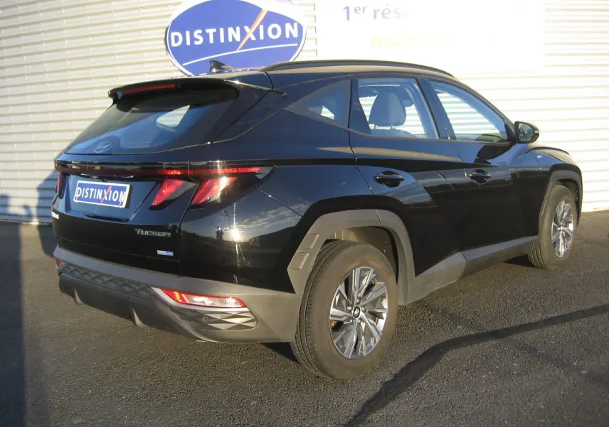 Vue 3/4 arrière droite d'un Hyundai Tucson noir 2022 hybride diesel avec feux arrière LED et jantes alliage.