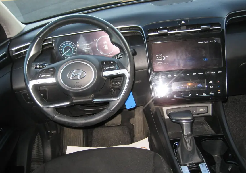 Vue intérieure du tableau de bord et volant noir du Hyundai Tucson III 2022 avec écran tactile et levier de boîte automatique.