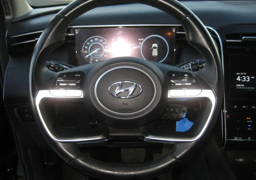Vue rapprochée du volant noir du Hyundai Tucson III 2022 avec tableau de bord numérique et commandes intégrées.