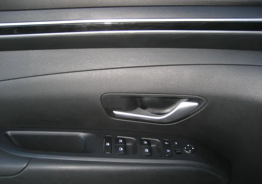 Poignée de porte intérieure côté gauche noire du Hyundai Tucson III 2022 avec commandes électriques des vitres et rétroviseurs.