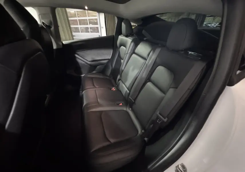 Vue intérieure côté droit sur la banquette arrière en cuir noir du Tesla Model Y blanc 2022 Grand Autonomie.