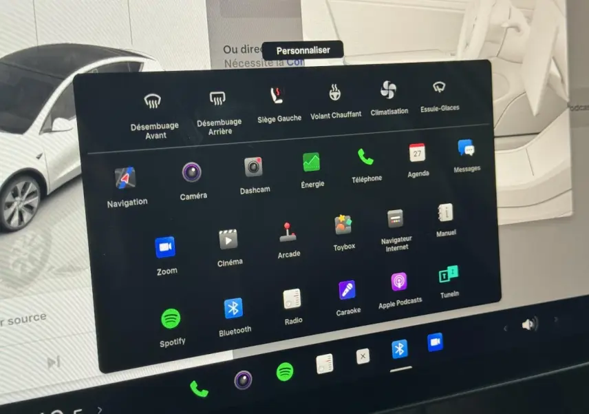 Écran tactile central affichant les options de confort et divertissement du Tesla Model Y blanc en intérieur.