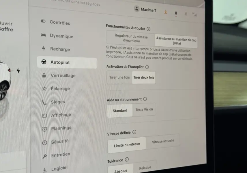 Écran tactile central affichant les réglages Autopilot dans l'habitacle d'une Tesla Model Y blanche de 2022.