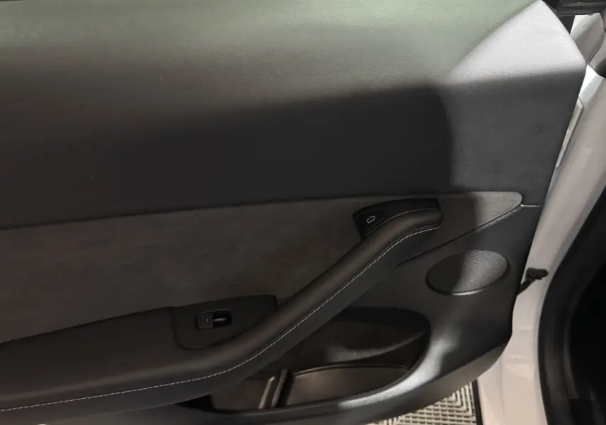 Gros plan sur la porte intérieure côté gauche blanche d'une Tesla Model Y 2022 avec garniture noire et poignée intégrée.