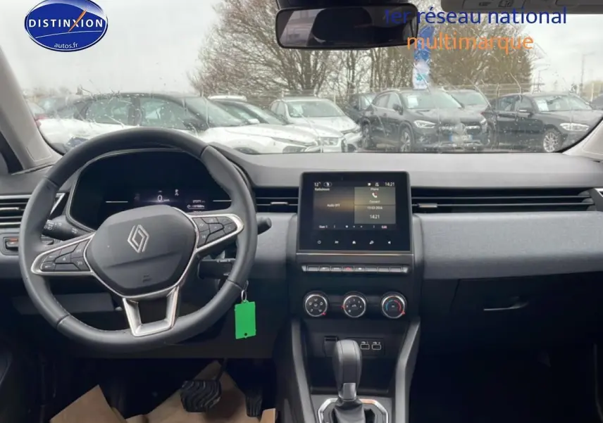 Vue intérieure avant de la Renault Clio V blanche, montrant le volant multifonction et l’écran tactile central.