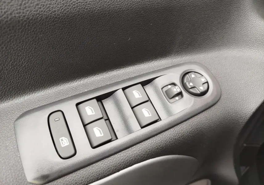 Gros plan sur les commandes de lève-vitres et réglage des rétroviseurs côté conducteur du Citroën Berlingo 2025 intérieur noir.