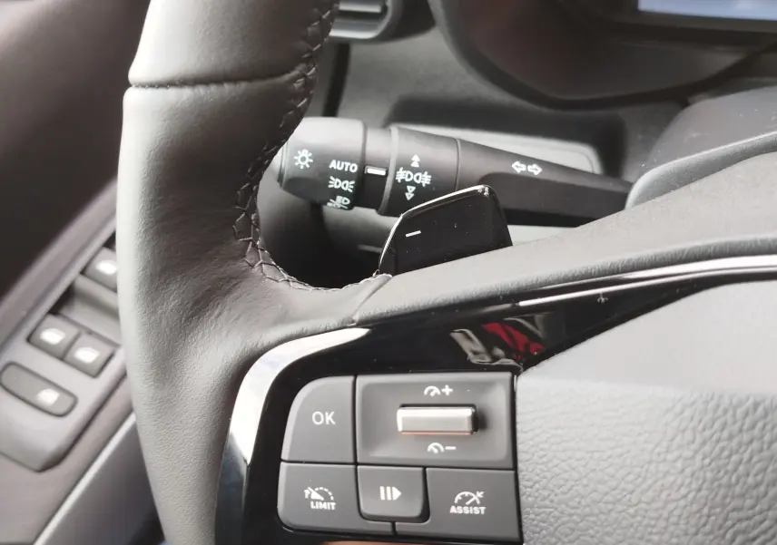 Gros plan sur le côté gauche du volant en cuir noir du Citroën Berlingo 2025, avec commandes intégrées et levier de clignotant visible.