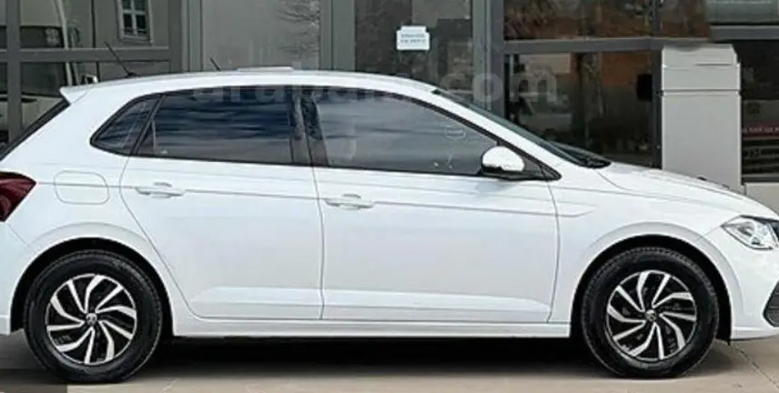 Vue de profil côté gauche d'une Volkswagen Polo blanche 2023 avec jantes noires et détails modernes.