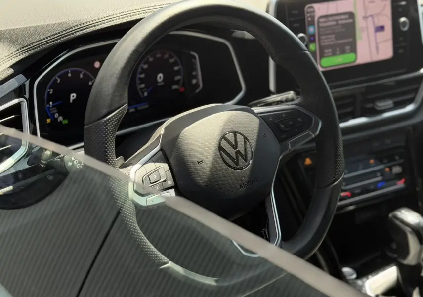 Vue rapprochée du volant noir multifonction Volkswagen T-Roc 2025 avec tableau de bord digital et écran tactile.