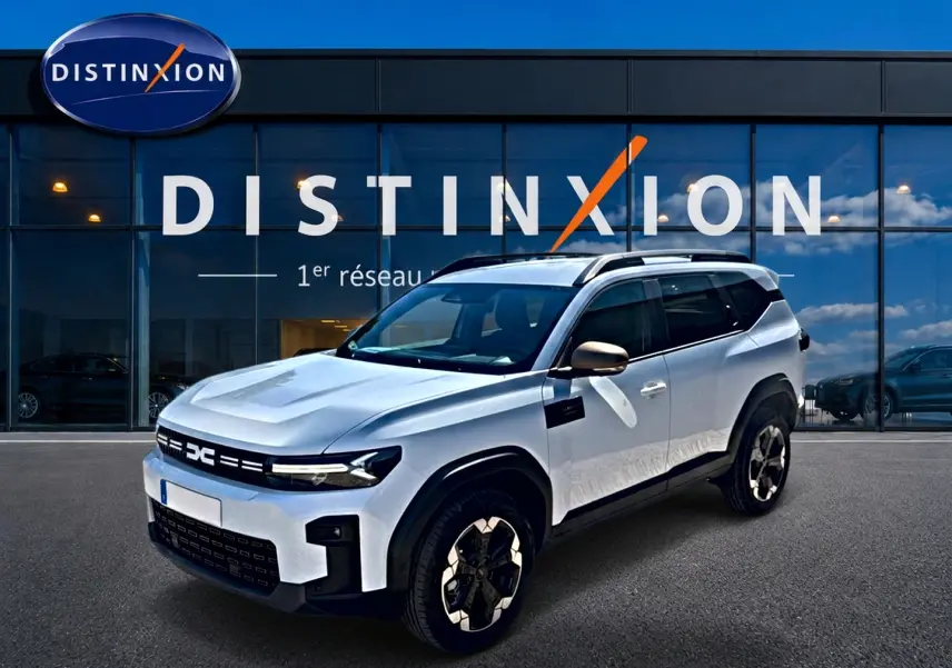 SUV Dacia Bigster blanc vu en 3/4 avant droit, avec barres de toit et jantes alu distinctives.