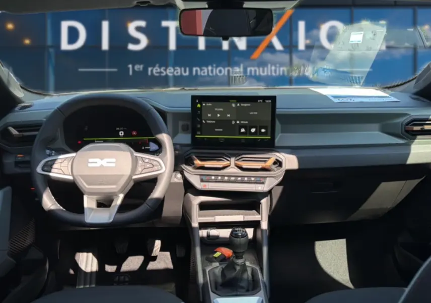 Vue intérieure avant du tableau de bord et volant du Dacia Bigster blanc avec écran tactile et boîte manuelle.
