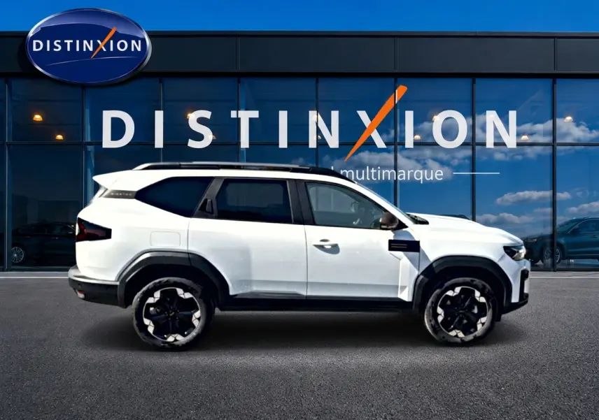 Profil droit du Dacia Bigster blanc 2026 avec jantes noires et toit contrasté devant une vitrine Distinxion.
