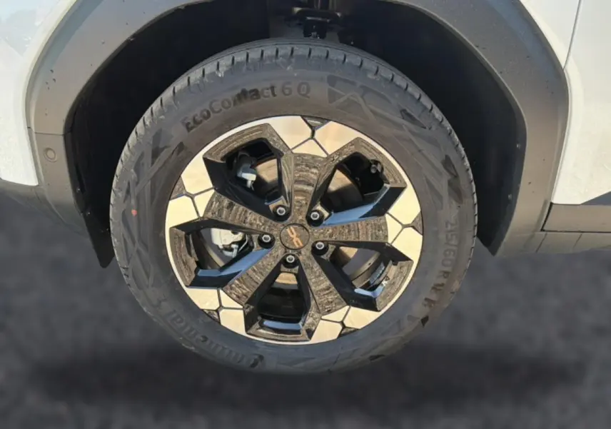 Gros plan sur la roue avant droite du Dacia Bigster blanc, mettant en valeur la jante alu bicolore au design moderne.