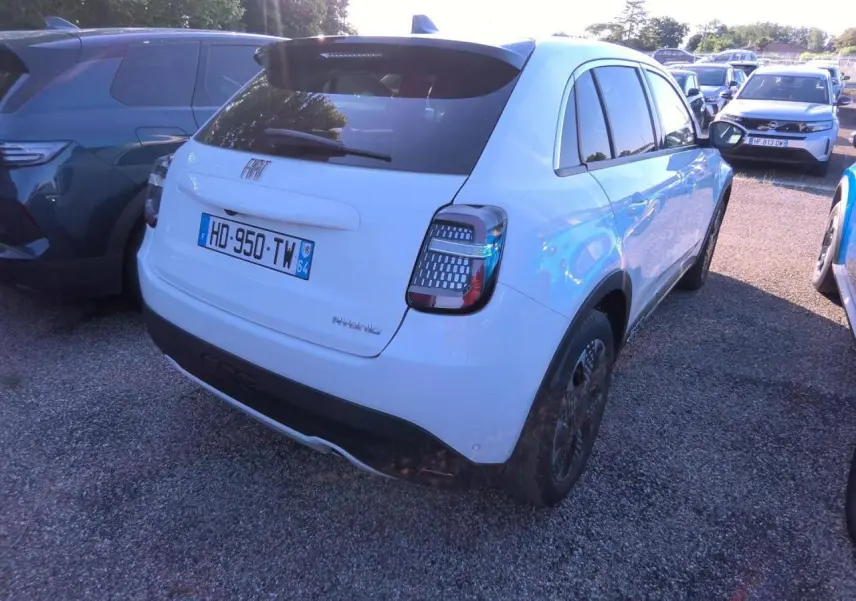 Vue 3/4 arrière droite d'une FIAT 600 blanche hybride 2025 avec feux arrière à motifs LED distinctifs.