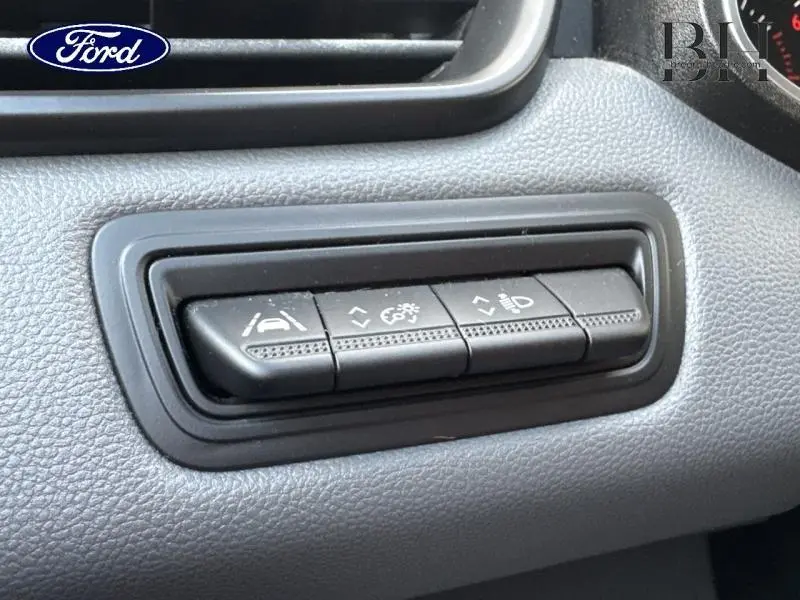 Gros plan sur les boutons de réglage d'assistance à la conduite dans un Renault Clio blanc, vue intérieure côté conducteur.