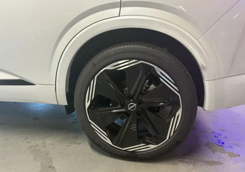 Gros plan sur la roue avant gauche du Nissan Qashqai blanc nacré avec jante noire et motifs blancs distinctifs.