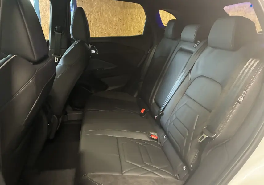 Vue latérale intérieure des sièges arrière en cuir noir du Nissan Qashqai 2025 blanc nacré métal avec toit noir.