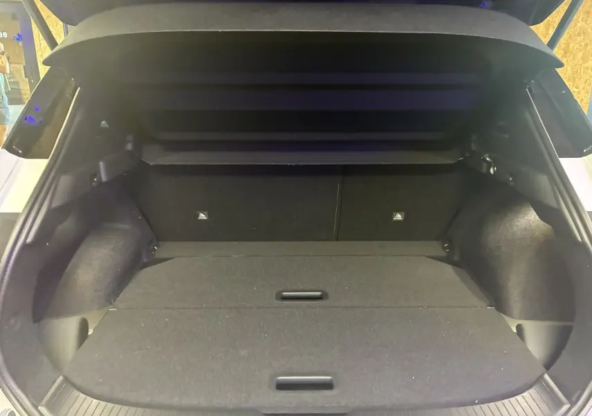 Coffre ouvert du Nissan Qashqai 2025 blanc nacré métal avec toit noir, montrant un espace de chargement spacieux et plat.